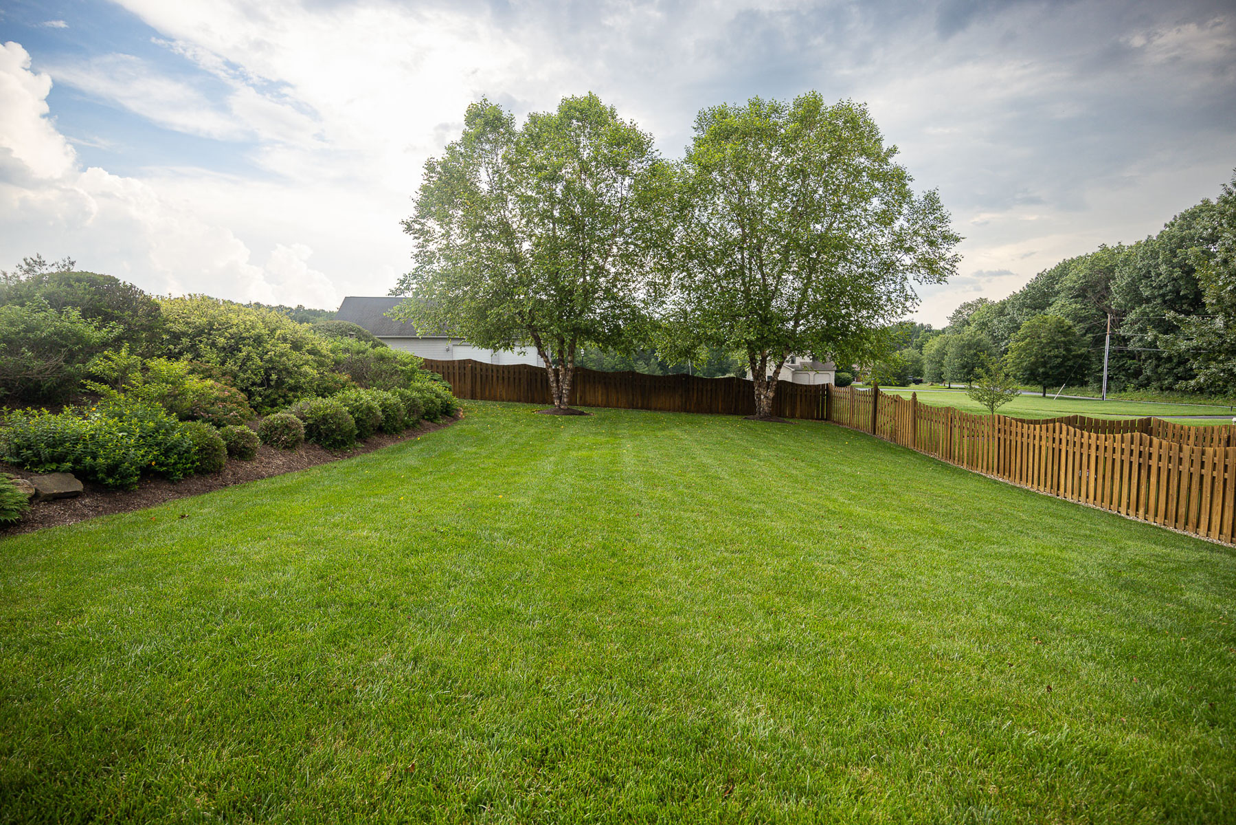 large fenced in green lawn with trees